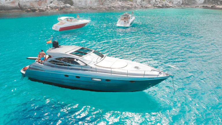 Ibiza kıyılarında iki tekneyle birlikte duran Byblos 3 motoryat berrak suda demirlemiş.