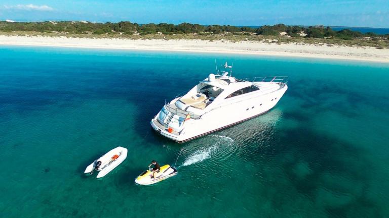 Kiralık motoryat Manzana, jet ski ve bot eşliğinde sığ koyda demirlemiş durumda.
