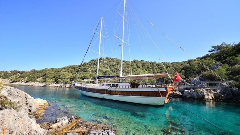 Queen Lila in a quiet bay, shows her elegant design in front of turquoise-coloured water.