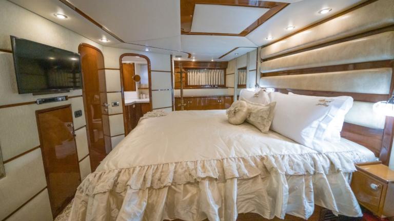 A luxurious bedroom with wardrobe, TV, bathroom, king-size bed and decorative pillows.