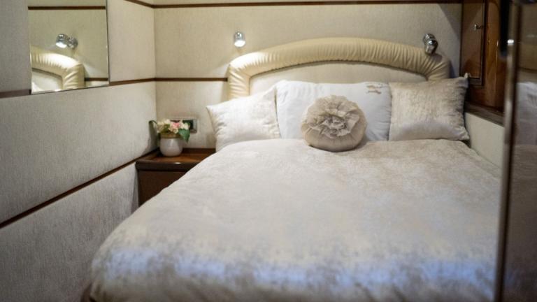 Nobly furnished bedroom with a bed decorated with beautiful pillows and mirror on the wall.