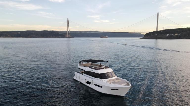 Die Motoryacht Suhan fährt auf dem ruhigen Meer mit Blick auf eine Brücke.