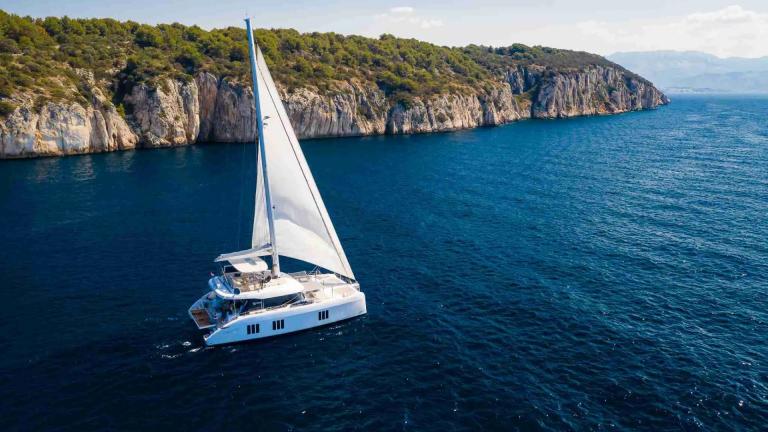 Роскошный катамаран Solitaire модели Sunreef 50 идёт под парусом вдоль живописного побережья Каштела.