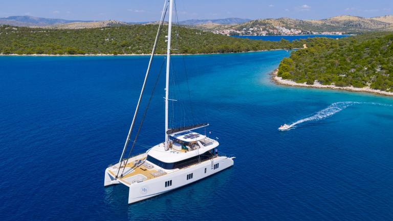 The Honeybird catamaran is anchored for charter on a sunny day in the turquoise bays of Šibenik.