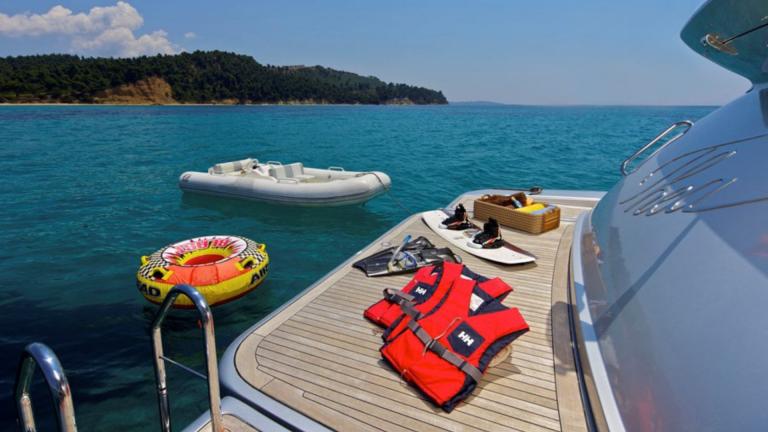 Life jackets, snorkeling gear, and a dinghy on the deck of the motor yacht Thea Malta off a picturesque coast in Greece.