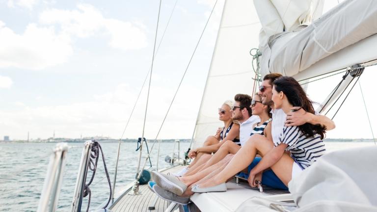 Fünf Personen genießen Erholung auf dem Deck einer Segelyacht auf dem Meer