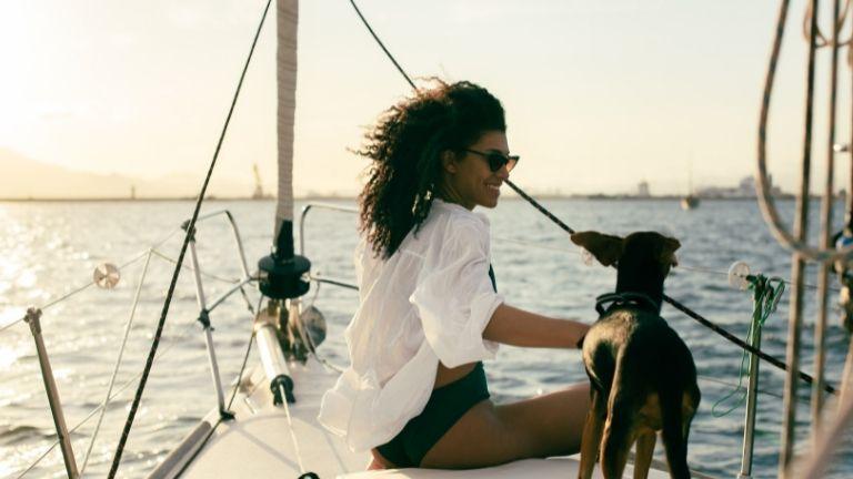 Eine Frau mit Brille und ihrem Haustier an Deck genießt einen Bootsurlaub.