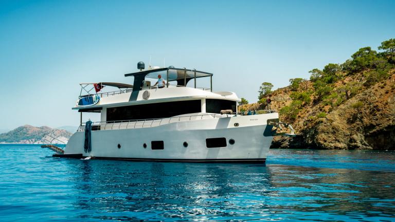 The Oggusto trawler yacht is anchored in a calm bay near Fethiye.