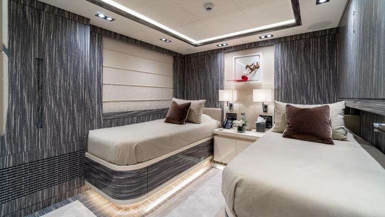 A stylish cabin on a yacht, equipped with two single beds, modern decor and soft lighting.