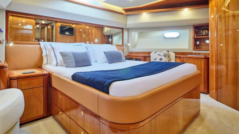 Elegant bedroom on a yacht with a large bed, wood paneling, and TV