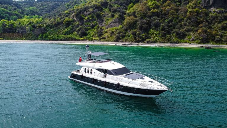 The Alfa F yacht is peacefully anchored on the water in a cove surrounded by greenery.