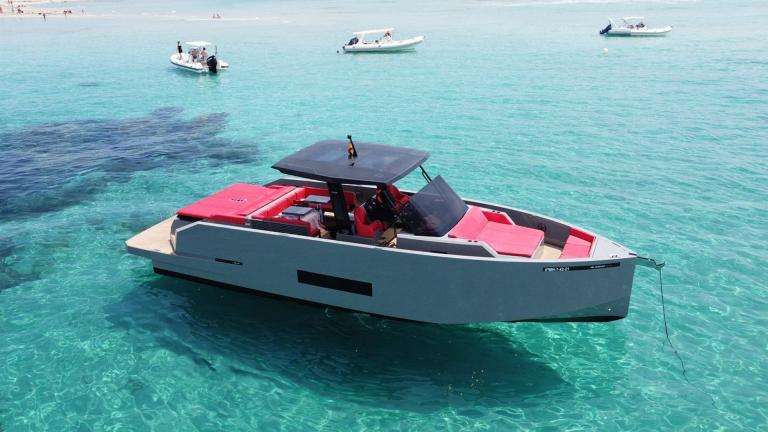 Die Motoryacht Aura besticht durch rote Sitzbereiche und modernes Design im türkisfarbenen Wasser.