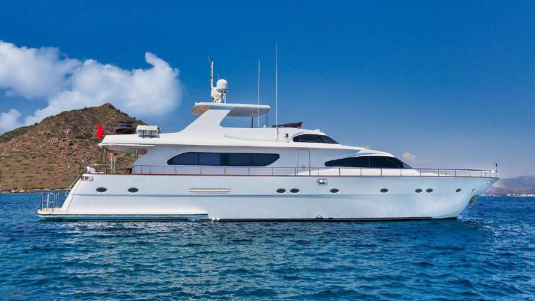Motor yacht Julem 1 anchored in Bodrum, surrounded by blue sea and mountain views.
