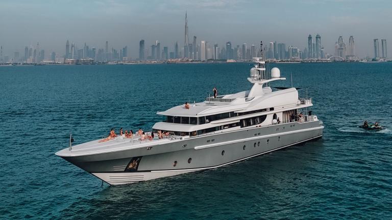 The yacht Thunder glides through the sea with a modern city skyline in the background.