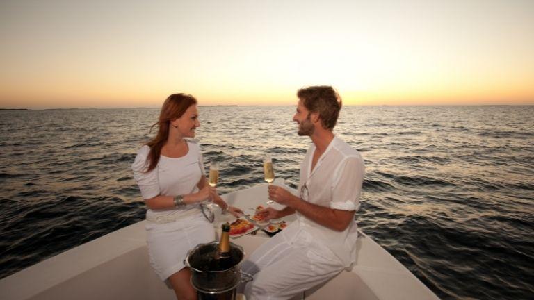 Ein Paar hat bei Sonnenuntergang ein romantisches Abendessen auf dem Boot.