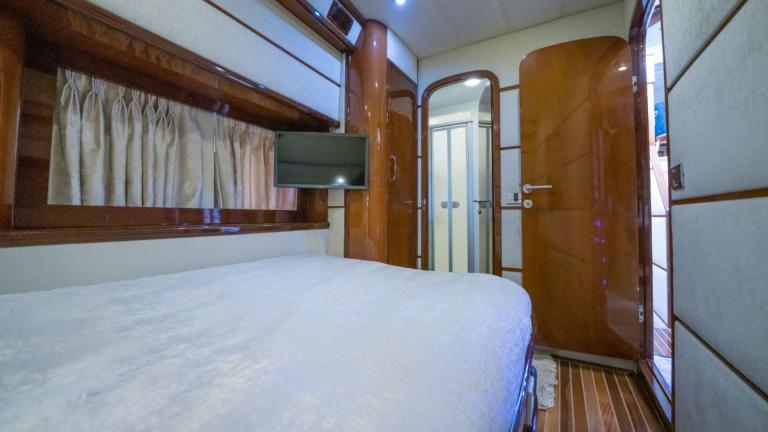 A cosy single cabin with bed, TV and mirror.