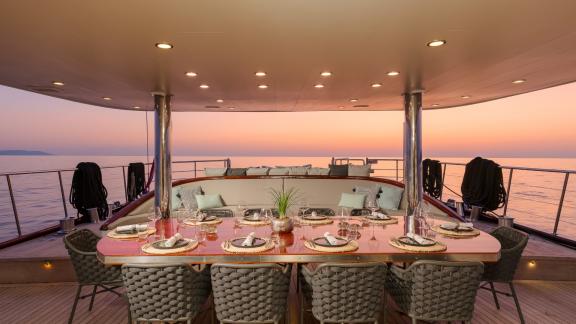 Элегантная обеденная зона на Lady Gita с видом на море на закате.