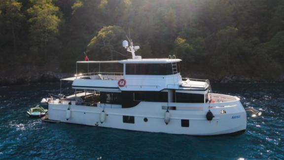 Trawler yacht Nayk 1 anchored in a wooded bay, offering a peaceful setting.