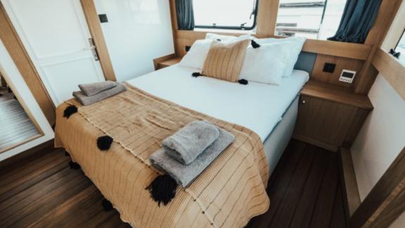 Cozy bedroom with a double bed on the yacht Nayk