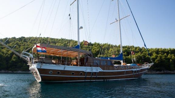 Die Gulet Malena liegt im klaren Wasser vor der bewaldeten Küste von Split, Kroatien.