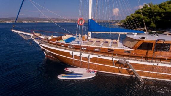 Die Gulet Malena liegt im klaren Wasser vor der Küste von Split, Kroatien, mit Paddleboards an der Seite.