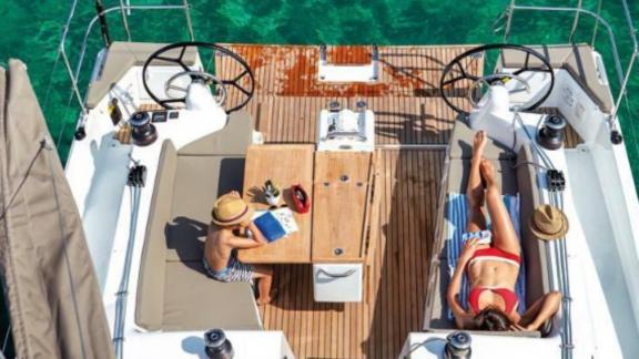 People sunbathing and reading a book on the aft deck of Sky Asya yacht at sea.