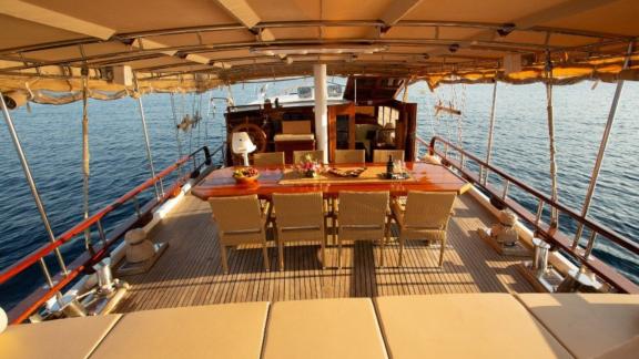 Deck of the gulet Malena with dining table and cosy seating areas, surrounded by the sea in Split, Croatia.