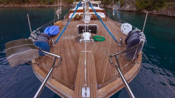 The foredeck of a sailing boat with a view of the bow and the surrounding landscape.