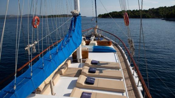 Sun deck of the gulet Malena with sunbeds, surrounded by calm waters and wooded islands in Split, Croatia.