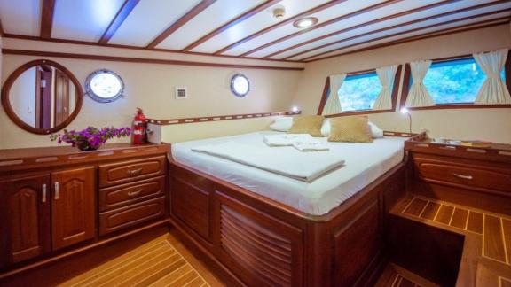 Cosy cabin on a sailing boat with a large bed and wooden panelling.