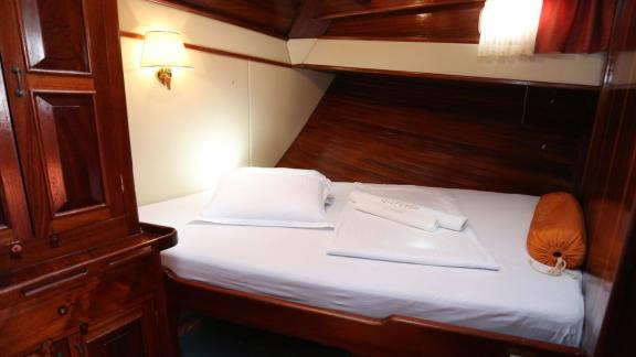 Interior view of one of the 8 cabins of the gulet in Marmaris harbour, showing a cosy bed and wooden furnishings.