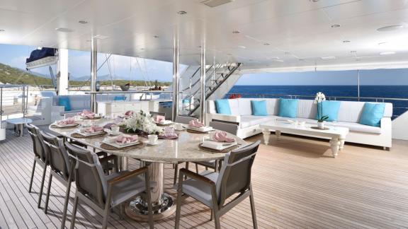 Luxurious outdoor deck of the Meira sailing yacht with dining area and cozy lounge.