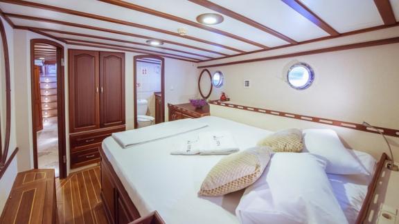 luxuriöse Kabine auf einem Segelboot mit einem großen Bett und eleganter Holzverkleidung.