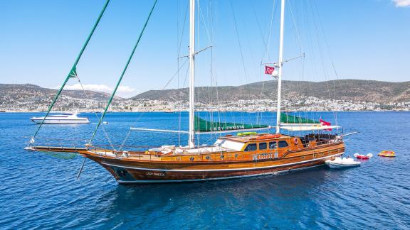 Die Gulet Lady Christa ankert in den blauen Gewässern von Bodrum, mit grünen Segeln und einer türkischen Flagge.