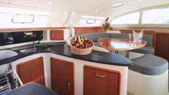 Inside the catamaran Vira Seyyah, the kitchen and seating area with a basket of fruit are visible.