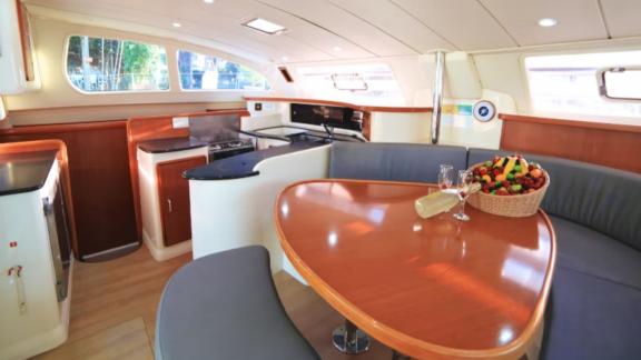 The interior of the catamaran Vira Seyyah features a cozy dining area with a kitchen and table.