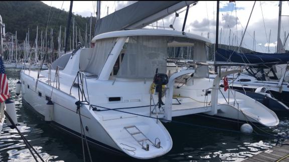 The catamaran Vira Seyyah moored in the marina, with its mast and aft deck visible.