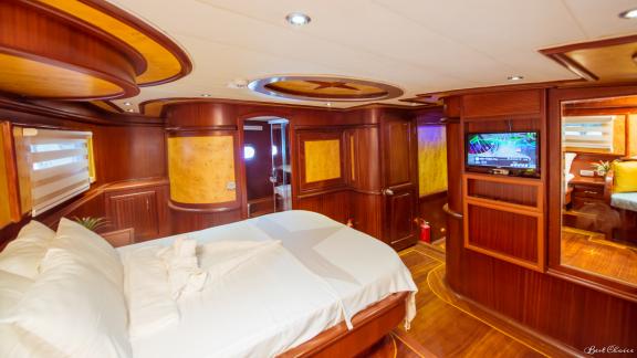 A luxurious cabin with a large double bed, TV, and elegant wood furnishings.