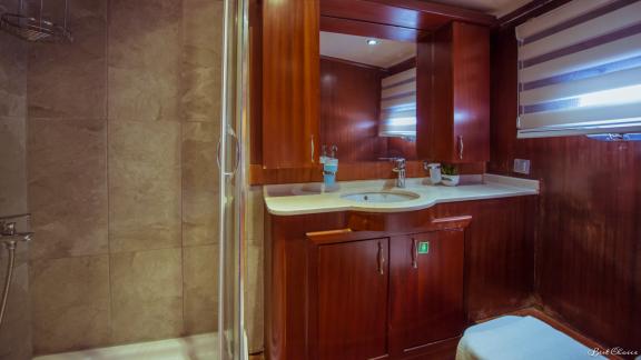 A stylishly designed bathroom with a shower and elegant wood furnishings on a gulet.