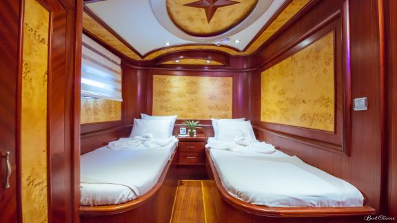 A stylish twin cabin with two single beds and luxurious wood furnishings.