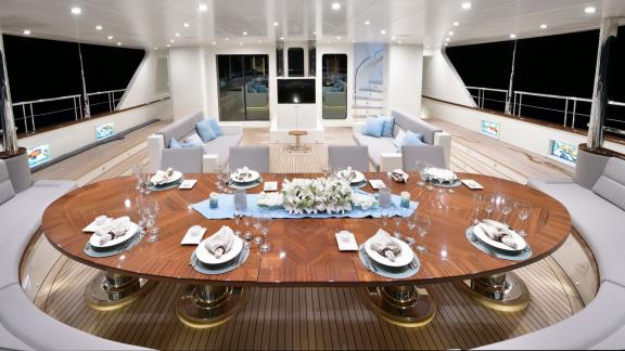 Luxurious outdoor dining area on the Meira sailing yacht with a stylishly set table and cozy seating.