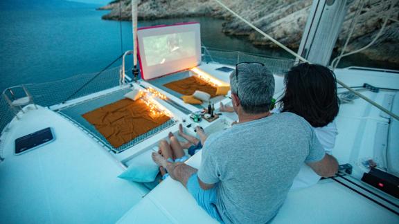 Ein Paar genießt einen romantischen Filmabend unter freiem Himmel auf dem Trampolin des Katamarans Marla Lagoon 450F.