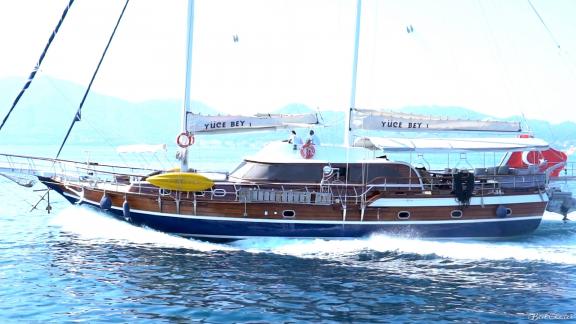 The Gulet Yüce Bey 1 sails dynamically through clear waters with visible sails.