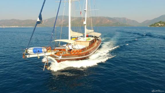 Die 24 Meter Gulet Yüce Bey gleitet dynamisch durch das türkisfarbene Wasser vor der malerischen Küste von Marmaris.