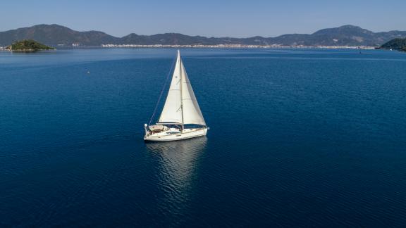 Die Segelyacht Eleven segelt auf dem offenen Meer mit Blick auf die Berge.