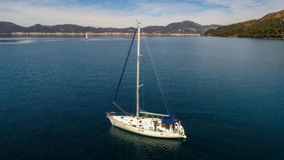 The sailing yacht Burda cruising on calm waters, with mountains visible in the background.