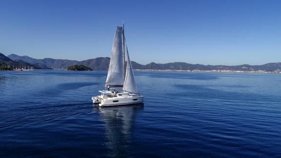 The catamaran Sky Maria sails on calm blue waters, enjoying the smooth sailing experience.