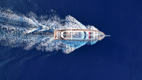 Atemberaubende Luftaufnahme einer eleganten Segelyacht, die durch das tiefe blaue Wasser fährt.