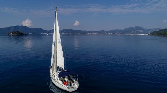 Die Segelyacht Kaçamak gleitet über ruhige Gewässer vor einer friedlichen Landschaft.