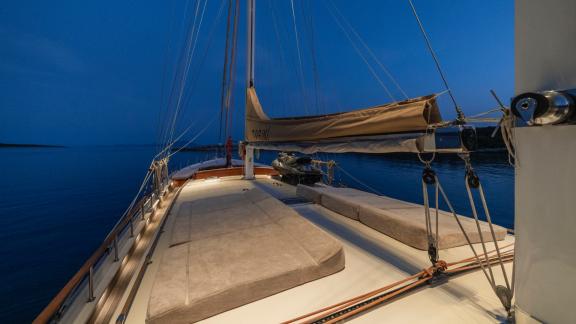 Beleuchtetes Deck der Gulet Torini bei Nacht, mit bequemen Liegeflächen und ruhigem, dunklem Wasser im Hintergrund.